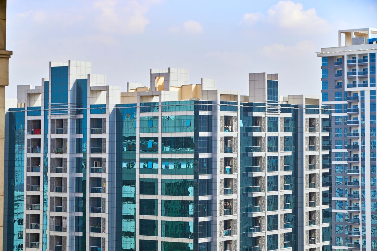 A cityscape view of modern high-rise buildings with reflective glass facades under a blue sky.